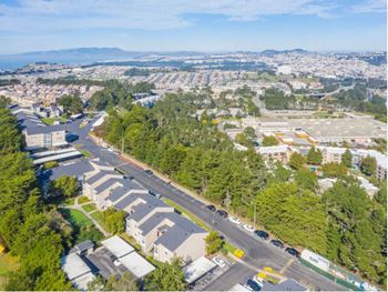 An aerial view of a neighborhood with cars on a road and trees and a city